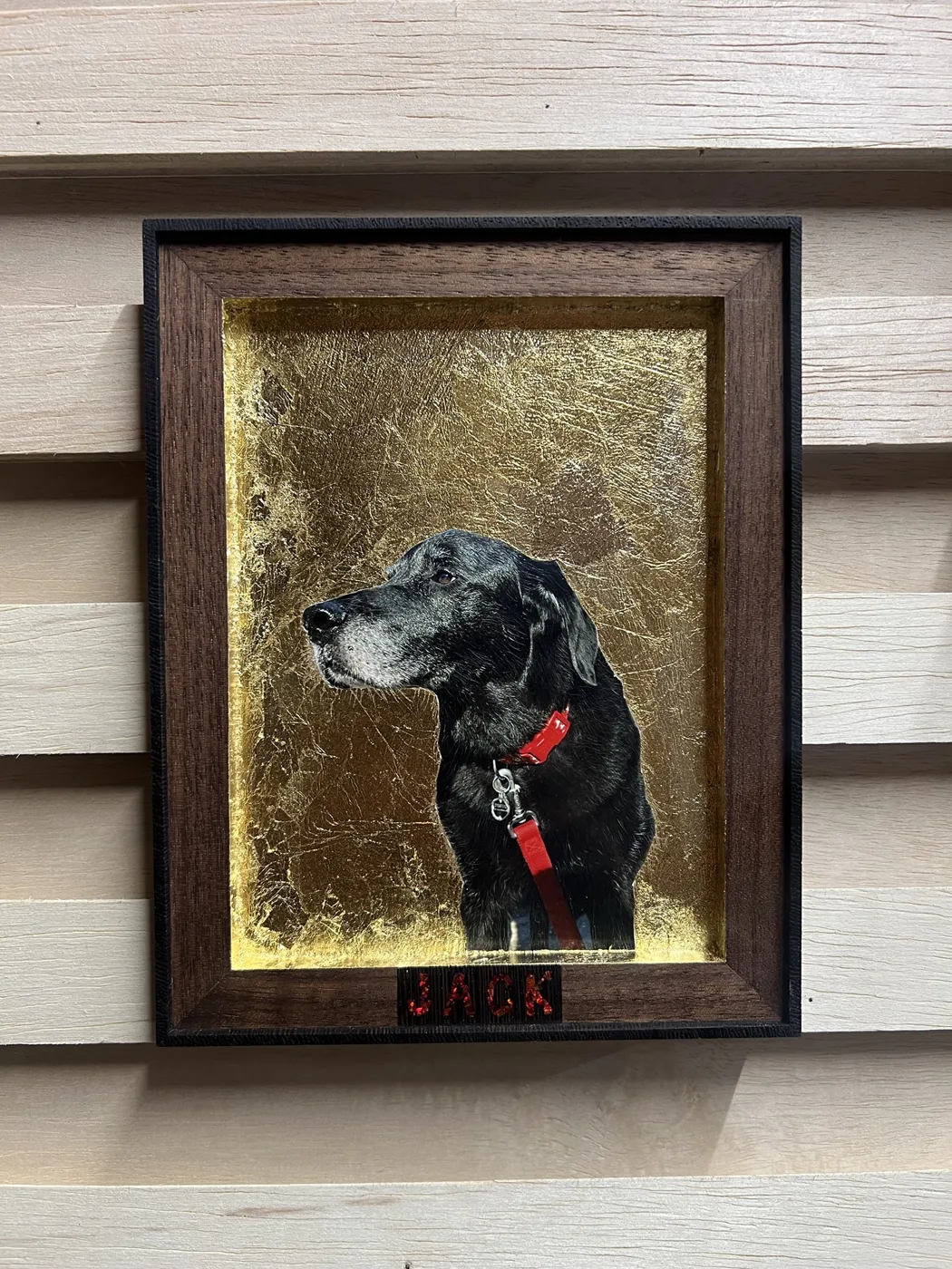 A black lab named Jack in a red collar, set against gold leaf inside a handmade walnut frame with JACK inlaid in red below