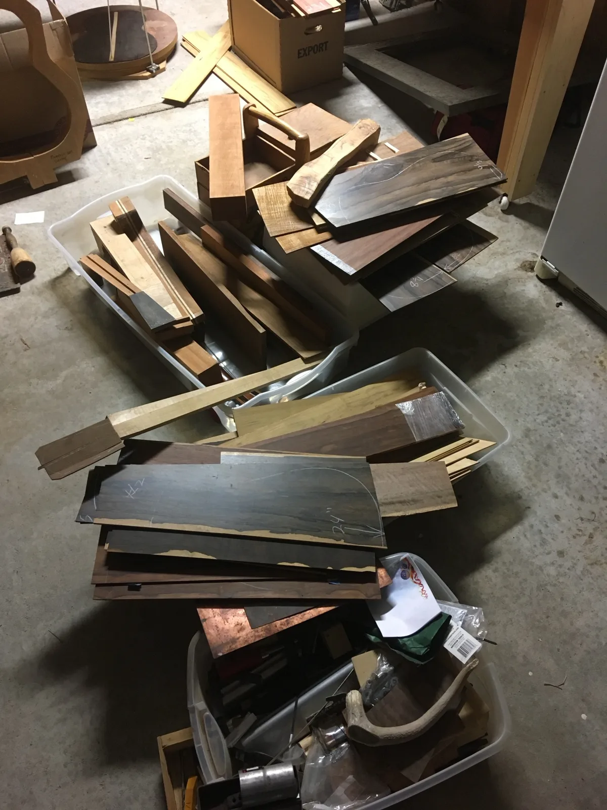 Bins and stacks of guitar tonewood on the garage floor: back and side sets, neck blanks and fretboard stock